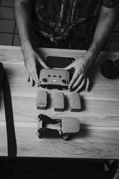 Monochrome view of hands assembling drone parts on a wooden table.