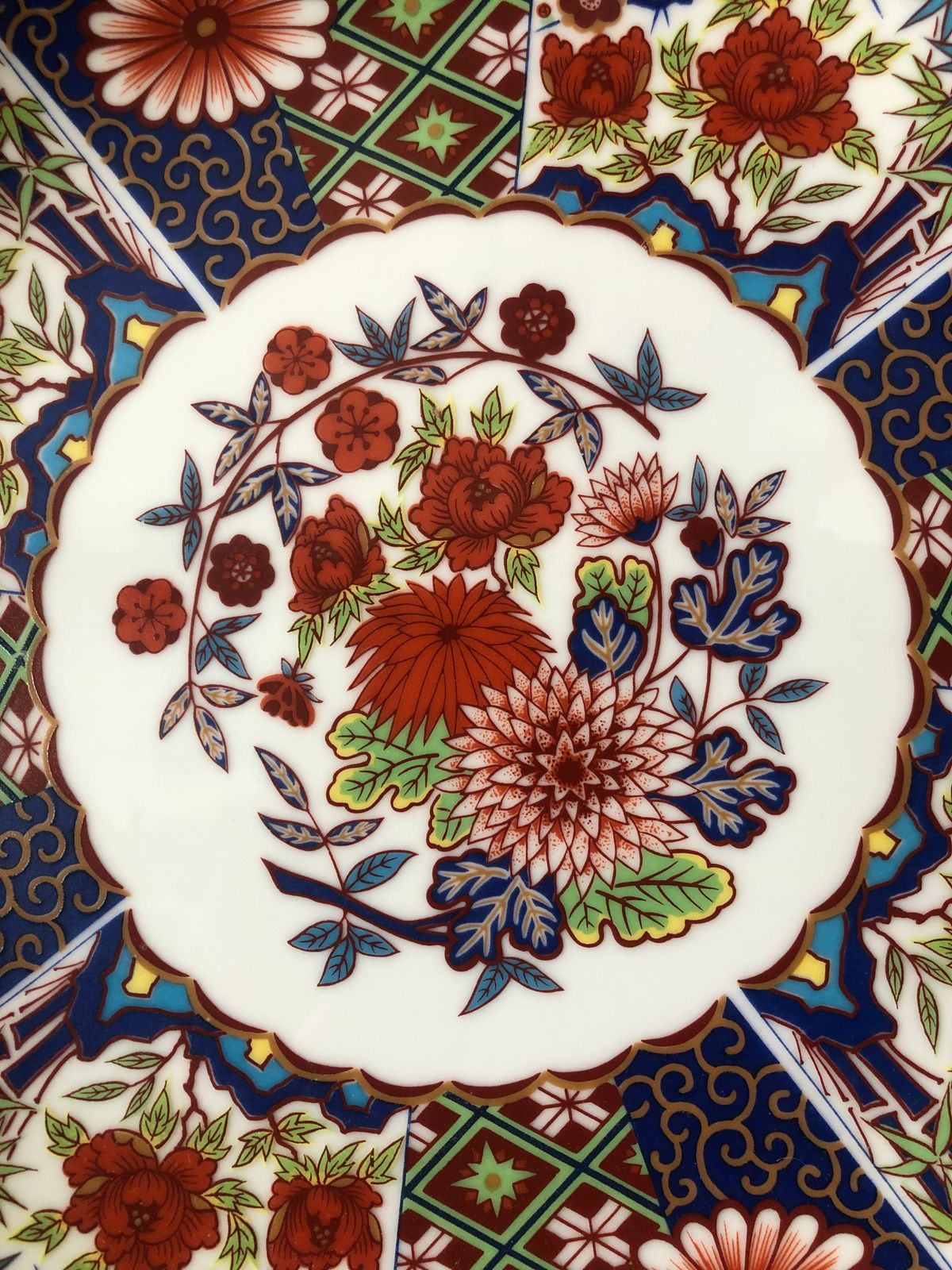 Close-up of a hand-painted floral pattern in red, cobalt blue and gold on a traditional ceramic plate