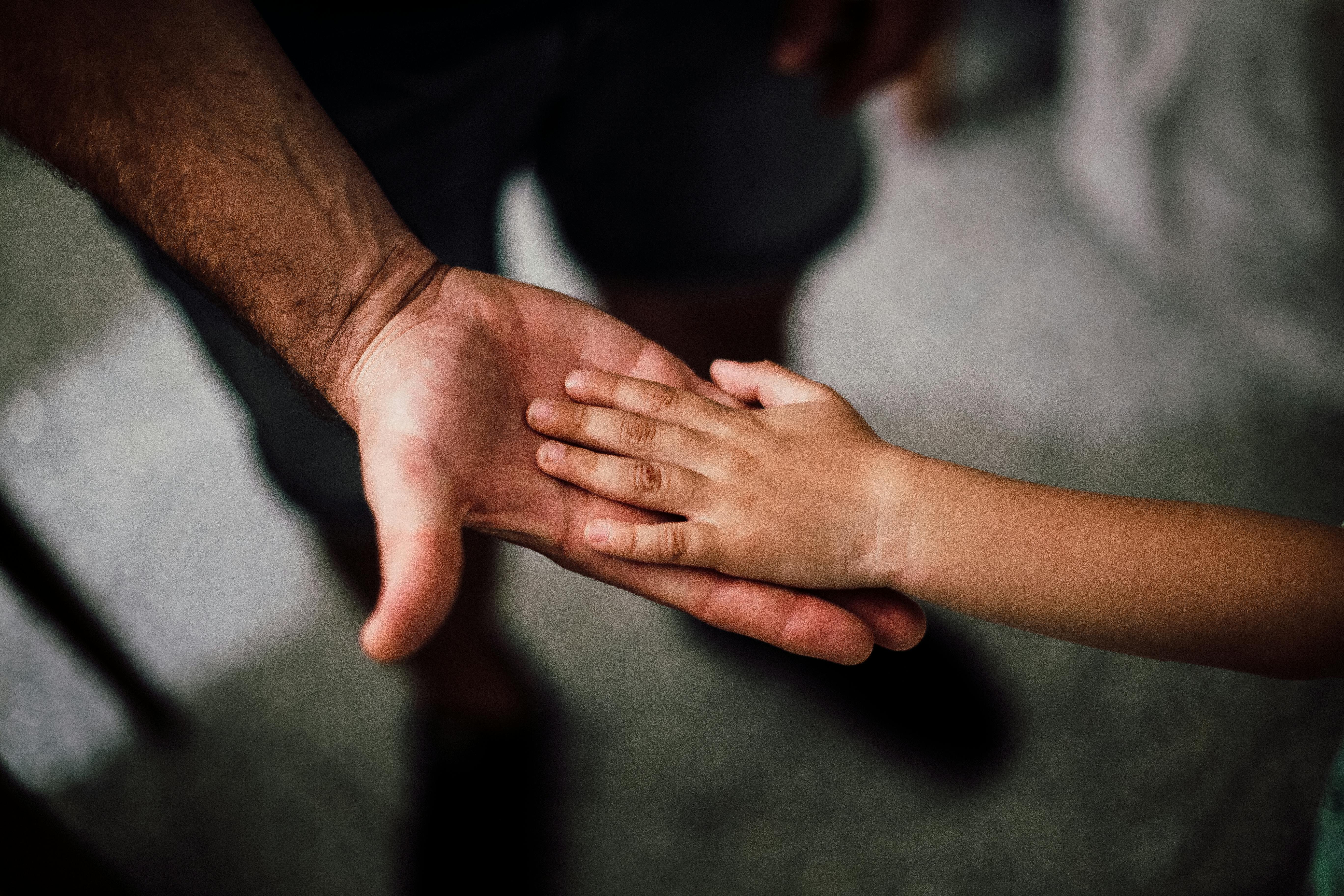 Selective focus photography of a man and a child's hand. | Photo: Pexels