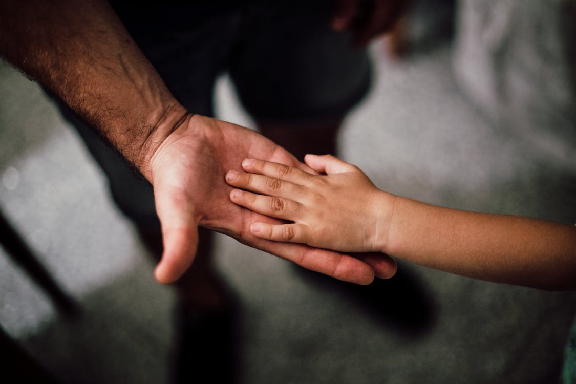 Selective Focus Photography of Child's Hand on Person's Palm