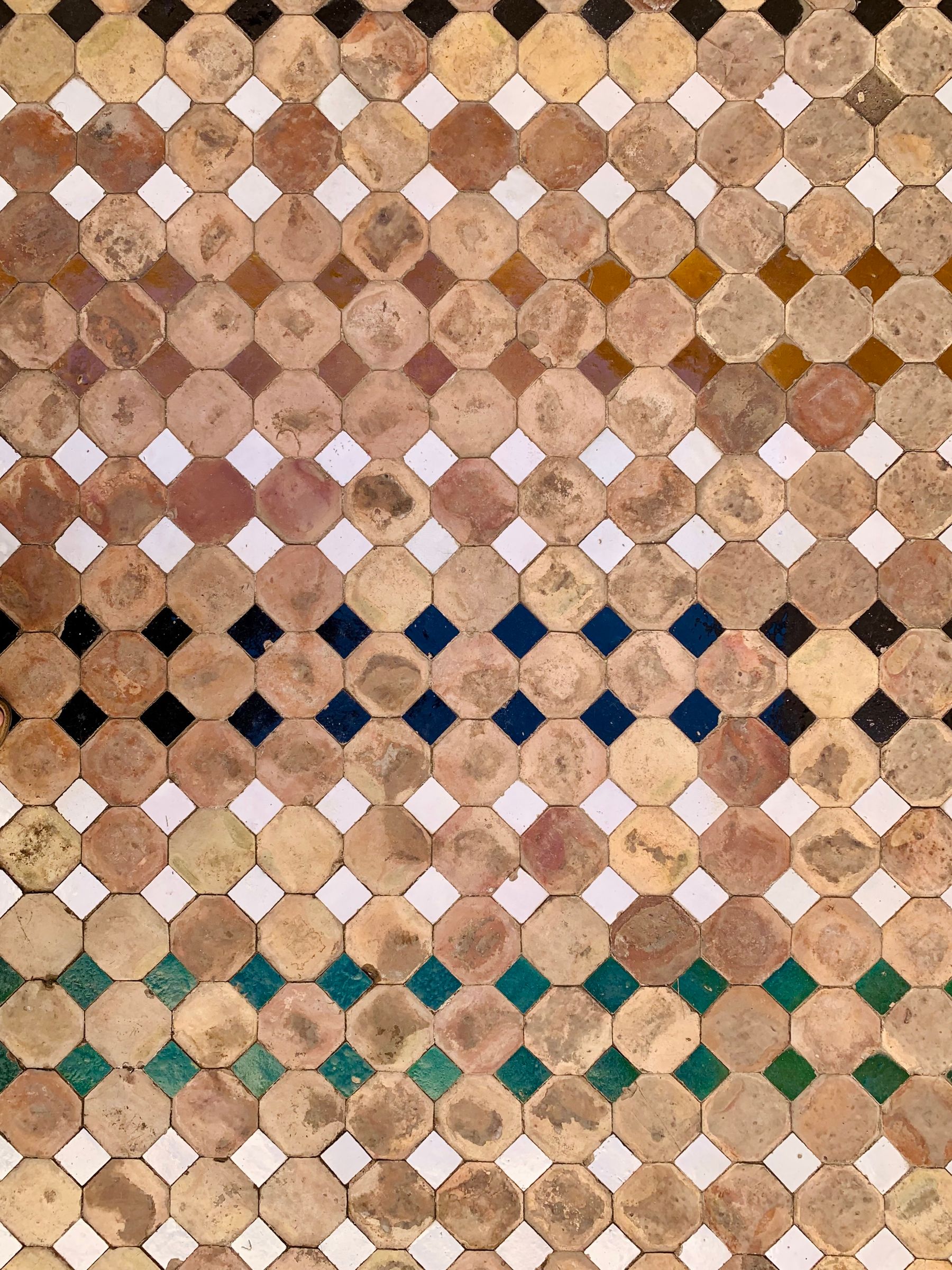 Geometric tile surface with cream and ochre polygons, small square inserts and dark color bands