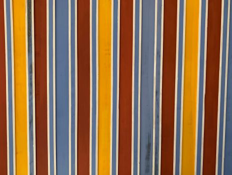 A colorful close-up of a striped painted wall with vertical blue, yellow, and red lines.