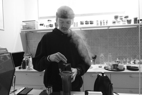 A barista preparing fresh coffee in a modern kitchen using an Aeropress.
