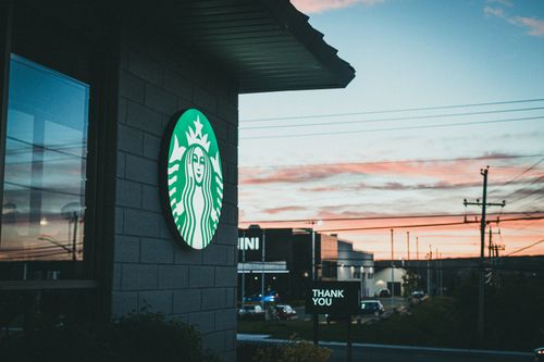 Free Evening cityscape with a coffee shop and vibrant sunset sky, showcasing urban life. Stock Photo