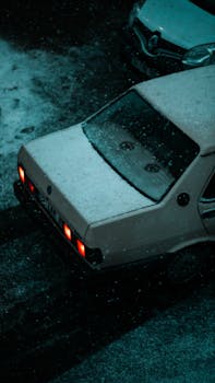 Retro car dusted with snow on an İstanbul street at night, evoking nostalgia.