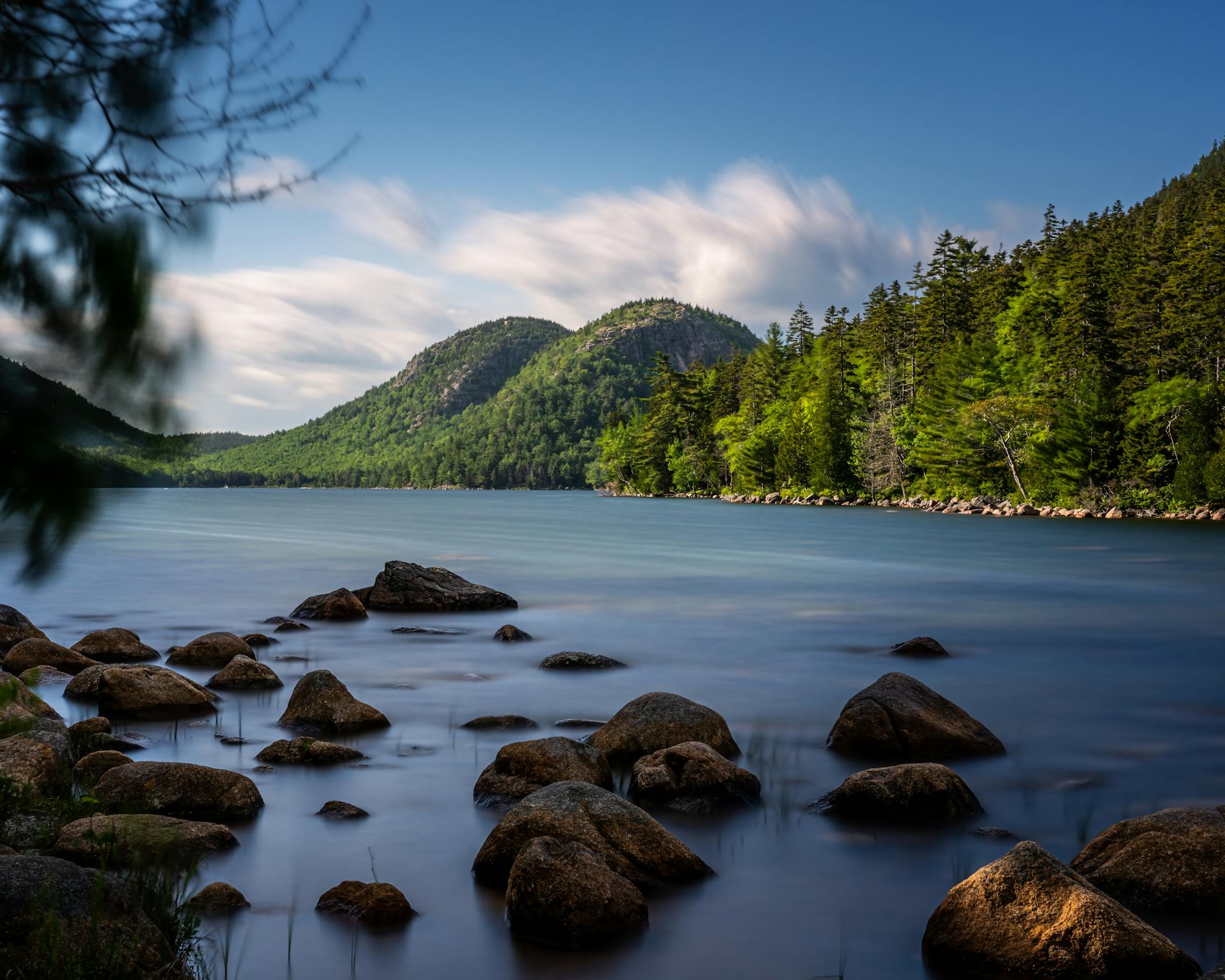 Serene landscape of Jordan Pond in Acadia National Park under a clear blue sky.