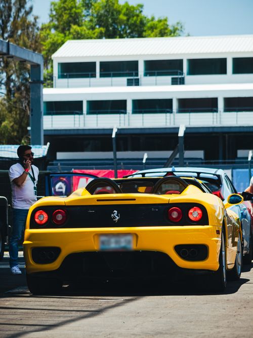 Free A sleek yellow sports car showcased at an outdoor car event, attracting enthusiasts. Stock Photo