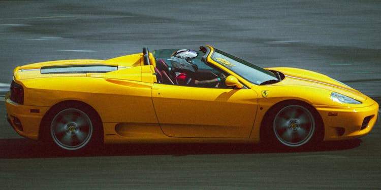 A Person Driving A Yellow Speeding Sports Car