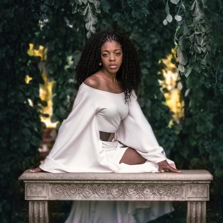 Woman In White Dress Sitting On Stone Bench