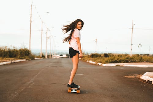 Frau, Die Skateboard An Der Straße Reitet