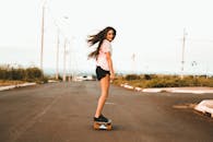 作为一名年轻女子，在空旷的道路上滑板，享受自由的时刻