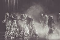 一位穿着飘逸服装的优雅女人在戏剧性的烟雾中翩翩起舞