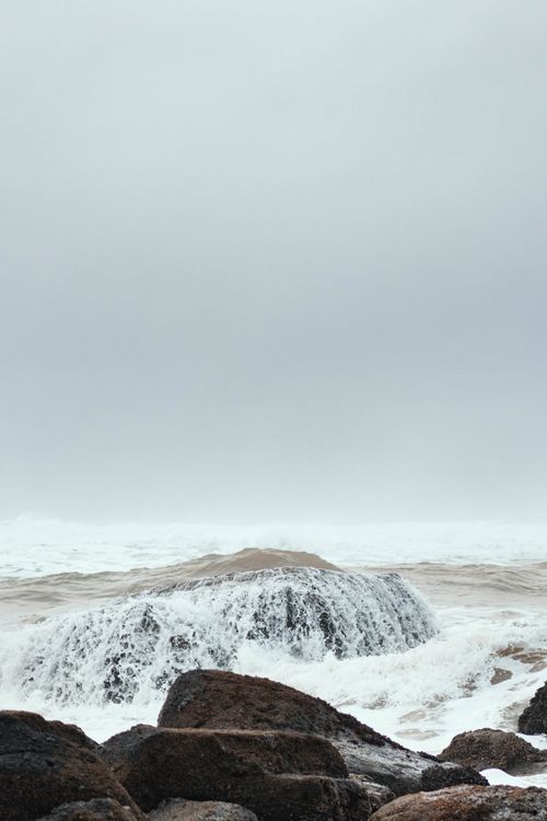 Free Captivating view of crashing waves on rocks under an overcast sky. Stock Photo