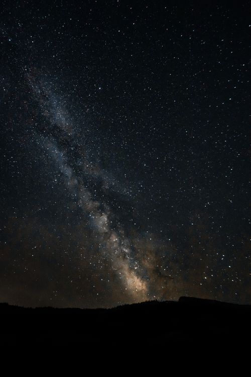 Free A breathtaking view of the Milky Way galaxy stretching across a clear night sky above mountain silhouettes. Stock Photo