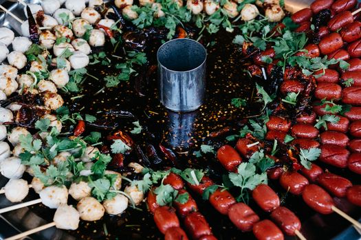 Close-up of flavorful grilled skewers with herbs and spicy sauce, perfect for food lovers.