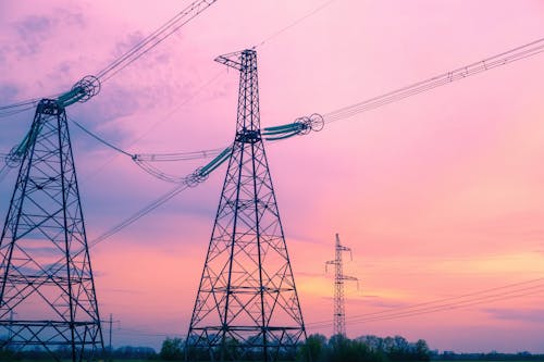 View of Electricity Towers against Pink Sky at Sunset 