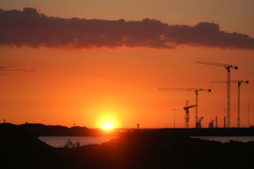 Free Steel Cranes Near a Body of Water at Sunset Stock Photo