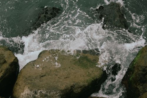 Free Dynamic coastal scene with waves splashing against mossy rocks. Perfect for nature themes. Stock Photo