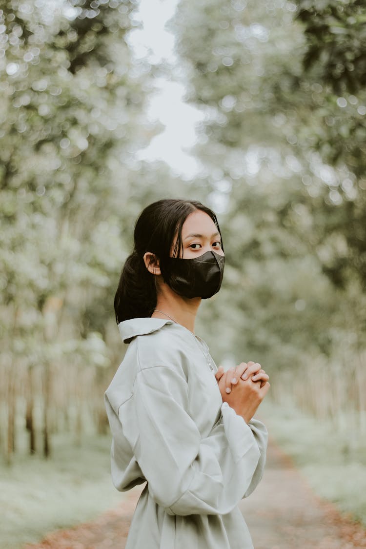 Brunette Girl Wearing Face Mask Standing With Hands Clasped