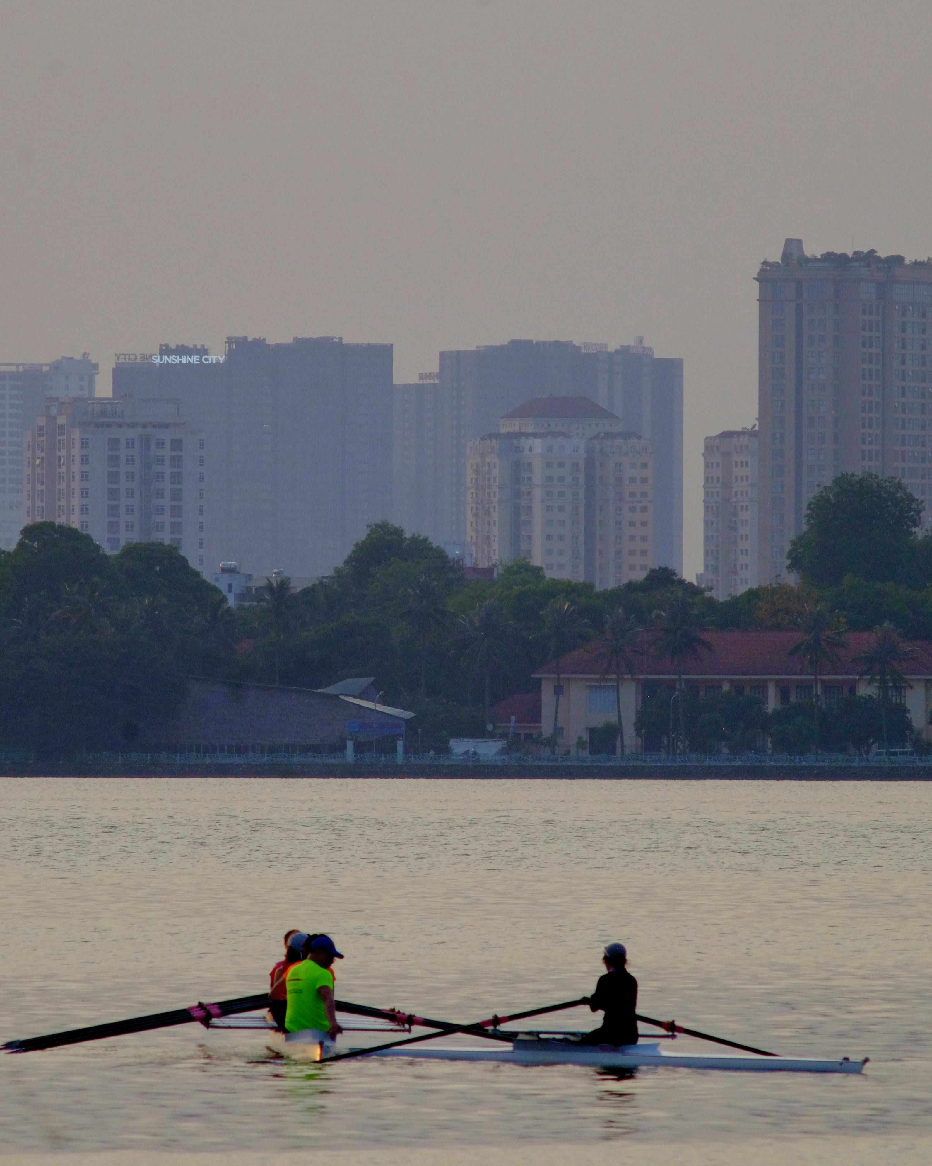 Kayakers enjoy a peaceful day on a lake with a city skyline backdrop, capturing urban leisure.