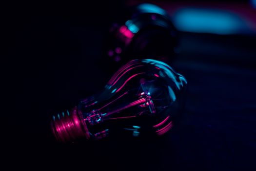 Dramatic close-up of a light bulb illuminated by vibrant neon lighting, evoking a creative and technological ambiance.