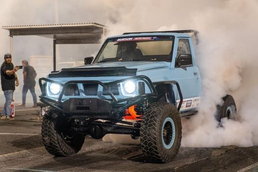 A blue off-road vehicle performing a drift in a smoky race setting in Mornington, Australia.