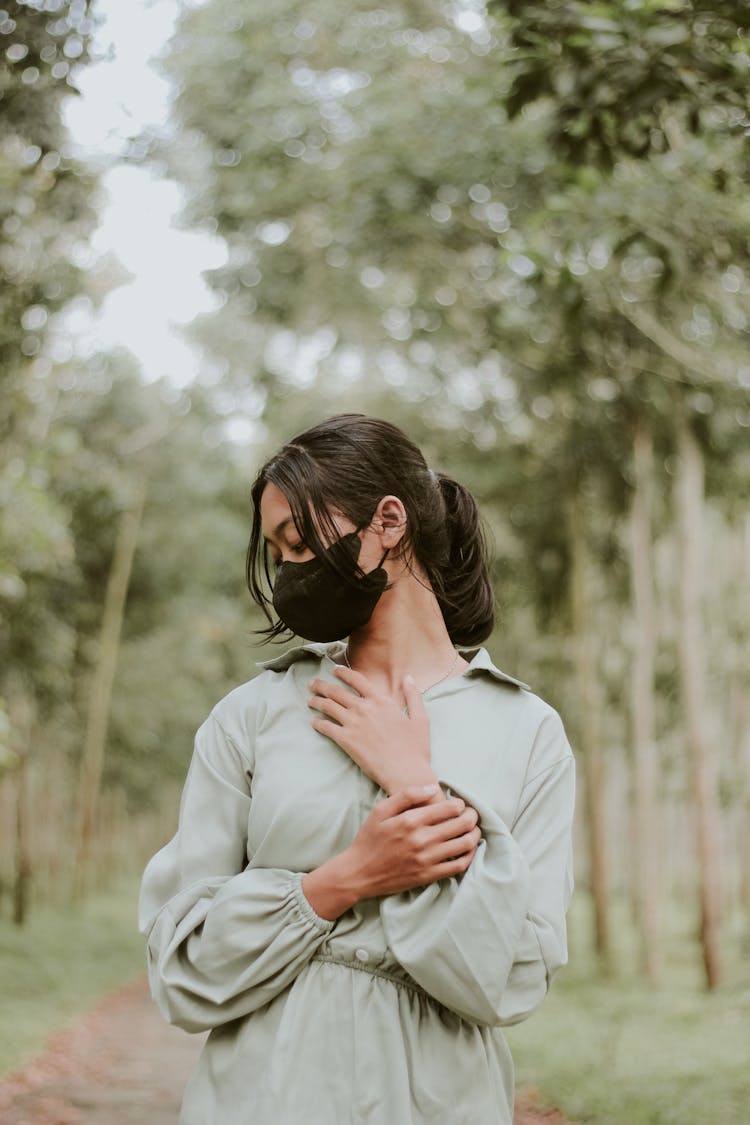 Young Woman In Black Face Mask Standing In Park