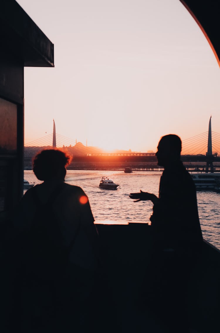 Silhouette Of Men Talking Near A River