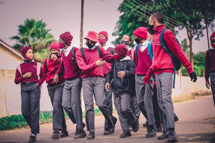 A Group Of Men In Uniform Wearing Face Masks Walking Together On Asphalt Road