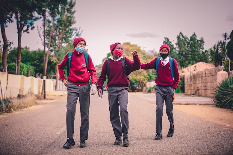 A Group Of Men In Uniform Wearing Face Masks Walking Together On Asphalt Road
