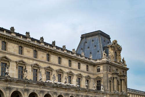 A Brown Concrete Building with Statues Under Blue Sky