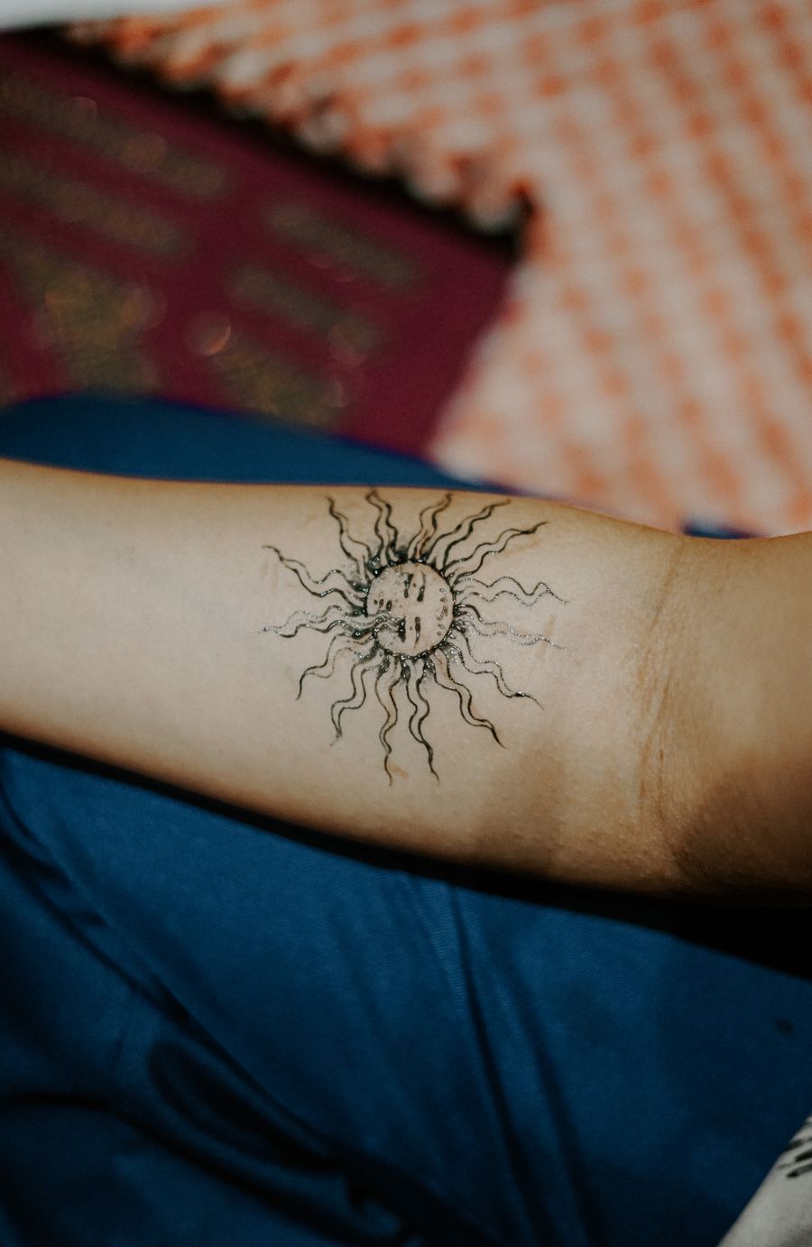 Fine-line sun tattoo on an inner arm