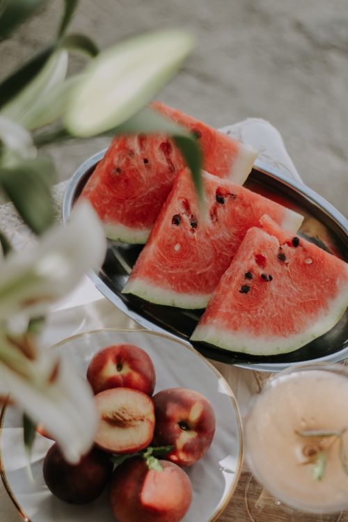Free A close-up of watermelon and peaches on a table, perfect for summer themes. Stock Photo