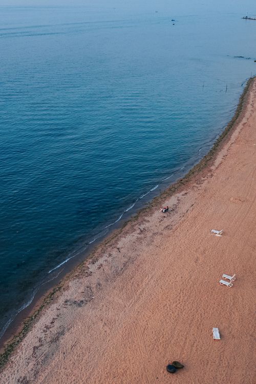 Free Serene aerial view of a sandy beach meeting calm ocean waters, perfect for nature lovers. Stock Photo