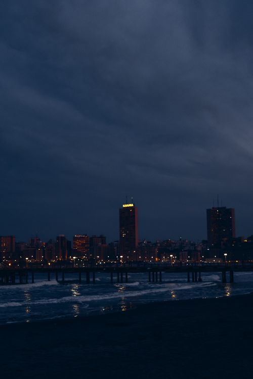 Free Night view of Mar del Plata with city lights and pier reflecting on the ocean water. Stock Photo