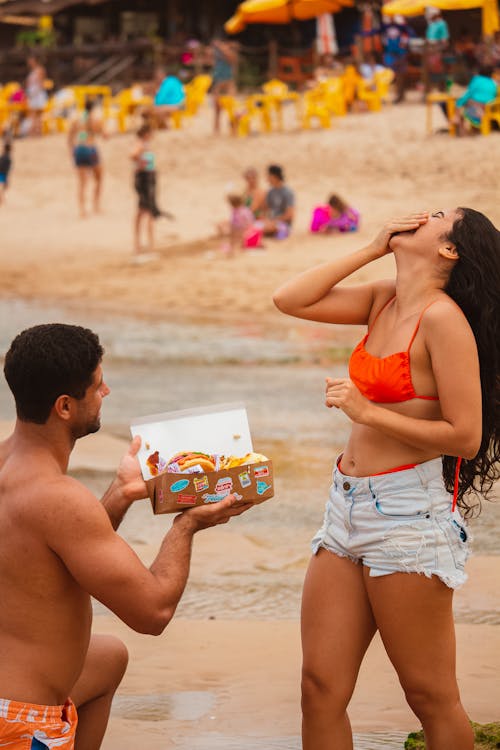 Man Holding a Box of Doughnuts Kneeling in Front of a Woman 