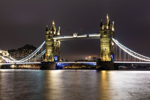 Free Stunning night view of the illuminated Tower Bridge in London, reflecting over the Thames River. Stock Photo