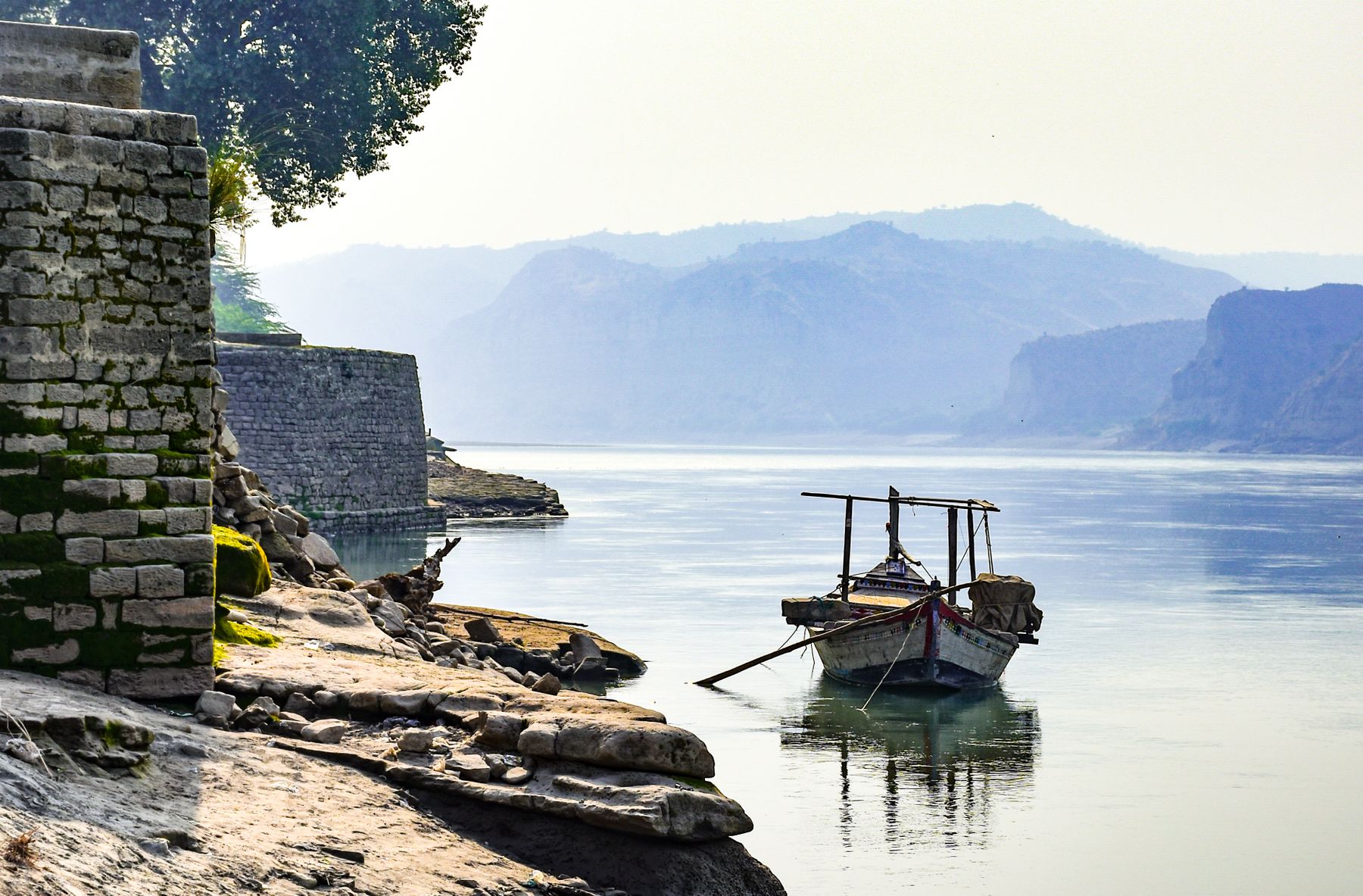 A scenic view of a tranquil river with a boat in Makhad, Punjab, Pakistan.
