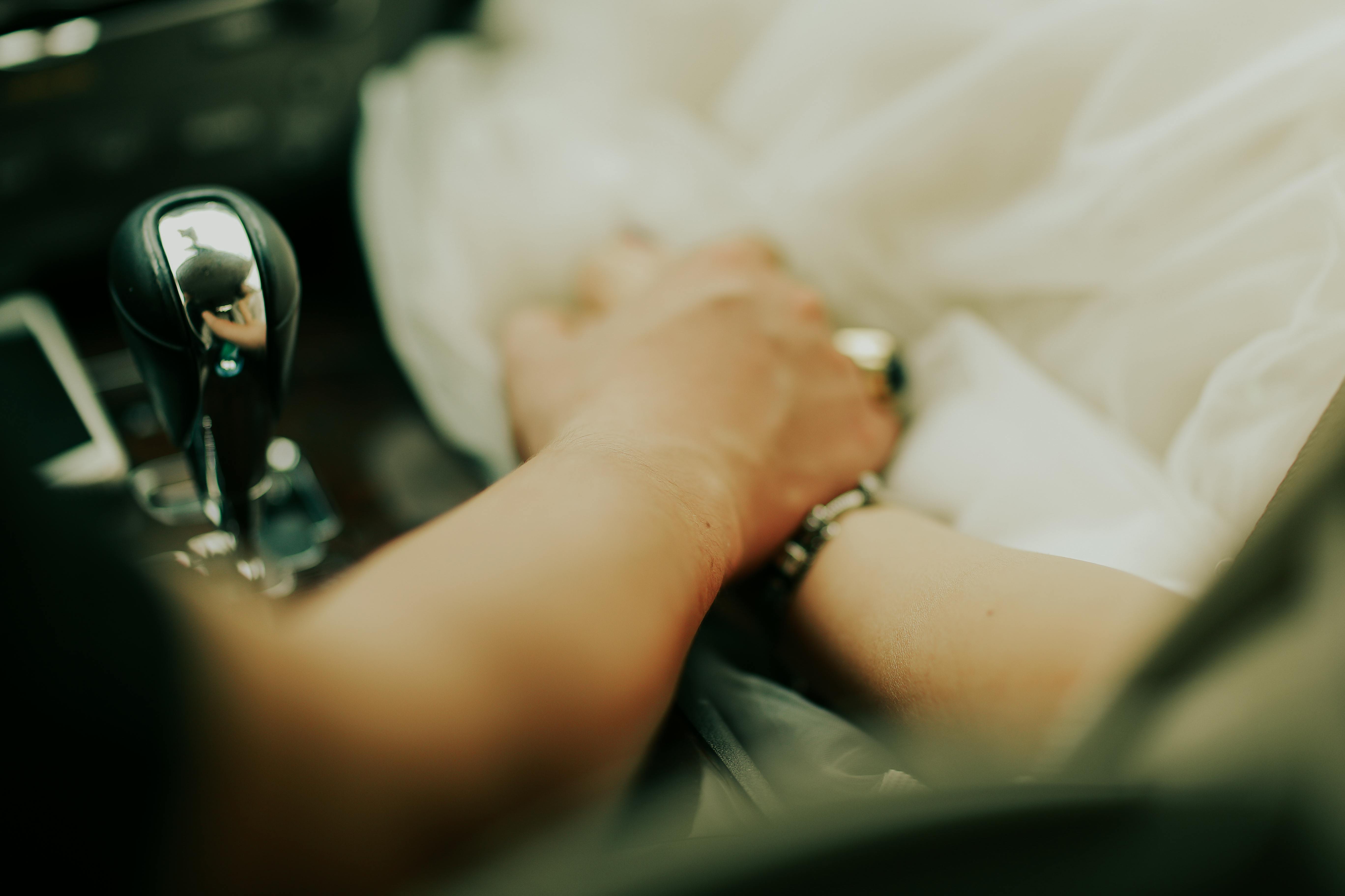 Intimate moment of a couple holding hands inside a car, symbolizing connection and romance.