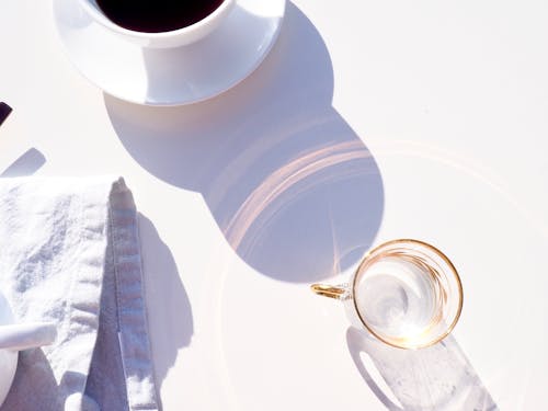 Free Empty glass reflecting sun near cup of coffee in morning Stock Photo