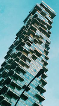 Low angle view of a uniquely designed skyscraper against a clear blue sky, showcasing contemporary urban architecture.