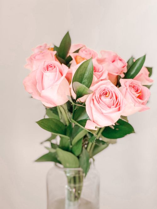 Free A bouquet of pink roses beautifully arranged in a glass vase, exuding elegance and charm. Stock Photo