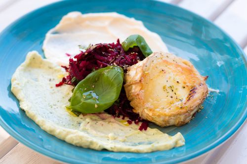 Free Close-up of a gourmet dish featuring spinach, beet salad, and creamy sauces on a blue plate. Stock Photo