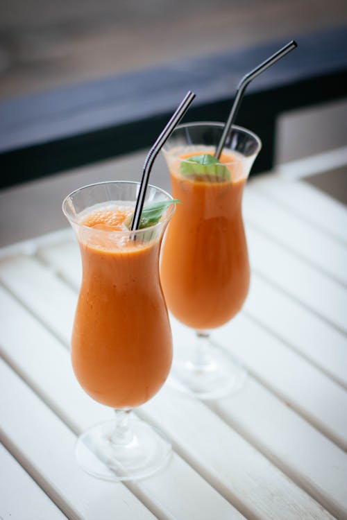 Фотография двух апельсиновых напитков в селективном фокусе