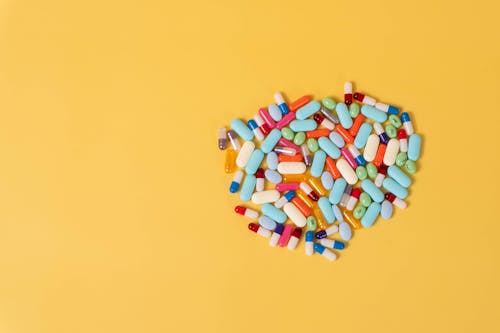 Close-Up Shot of Pills on Yellow Surface