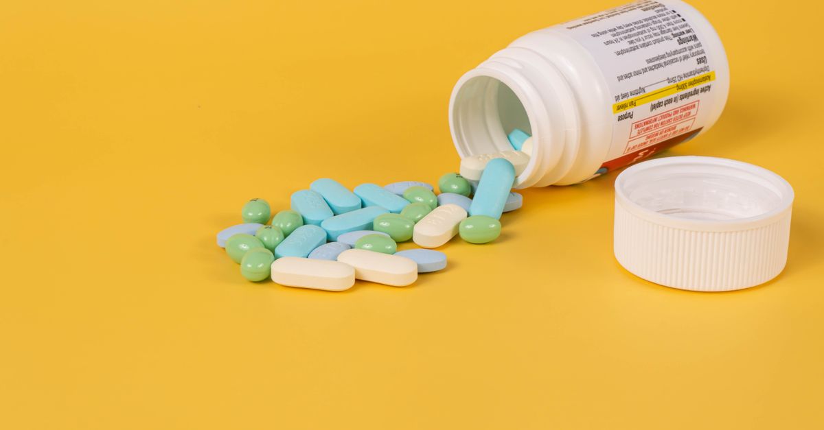 Pill bottle and pills on a yellow surface