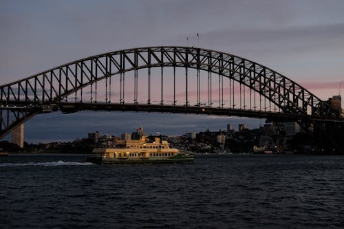 A Ferry Boat Sailing Under Sydney Harbour Bridge During Evening Sky