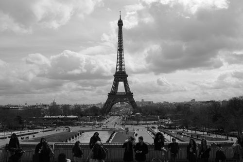 Free A monochrome photo showcasing the Eiffel Tower, Paris, with tourists in the foreground. Stock Photo