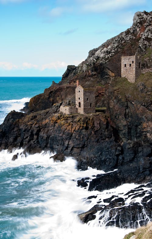 昼間の海の近くの崖にある2つの灰色のレンガの望楼