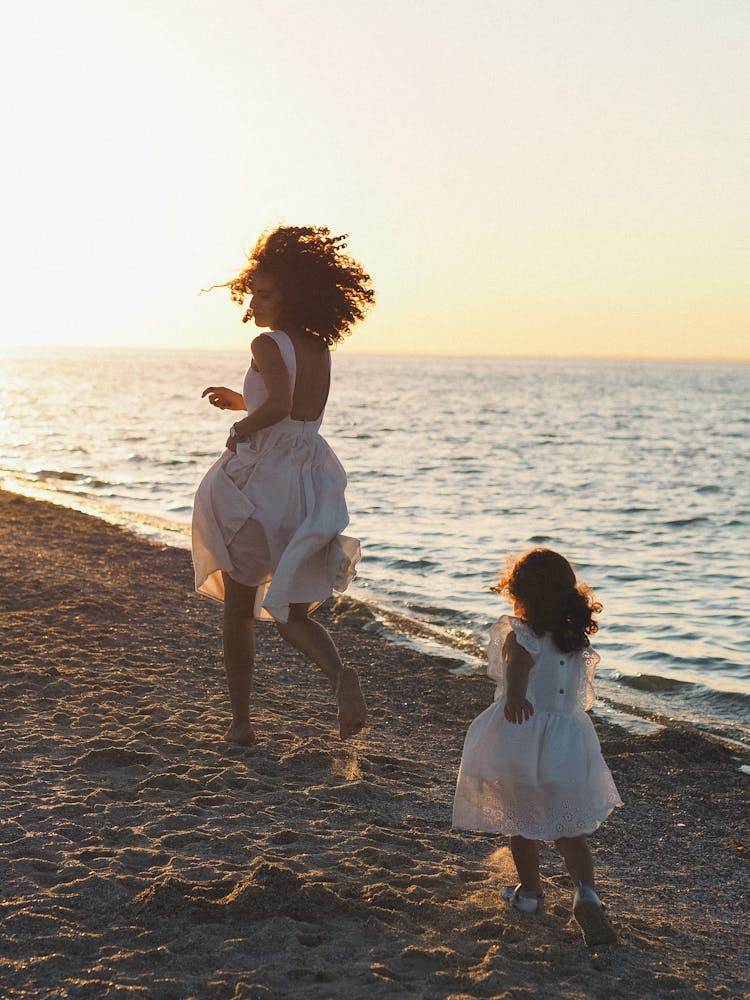 Mother And Daughter Running On A Beach 